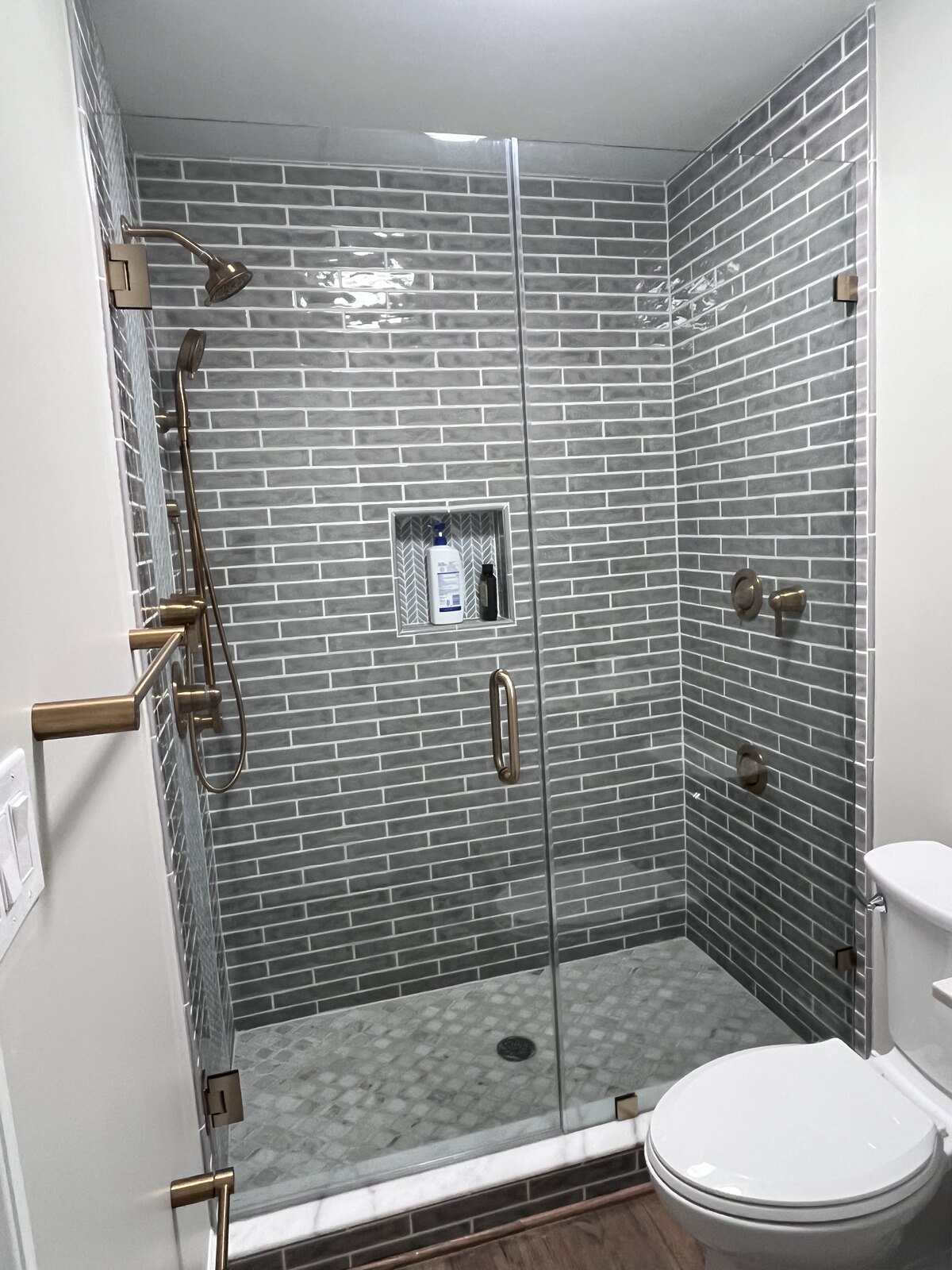 Luxury walk-in shower with subway tile and gold fixtures