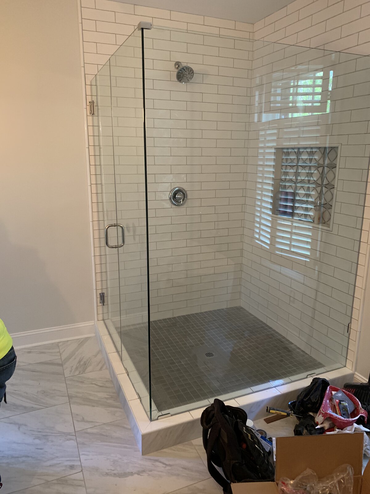 Gray tile shower with brushed gold fixtures and glass door