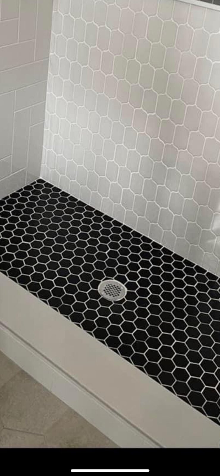 Shower with white hexagon walls and black hexagon mosaic floor