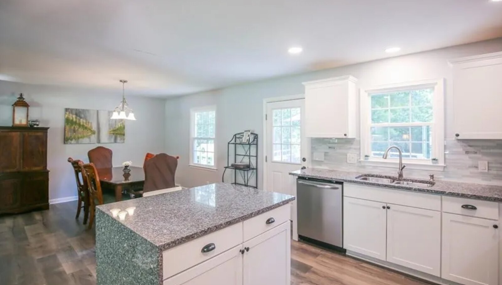 Renovated kitchen with white cabinets, granite countertops and linear glass backsplash
