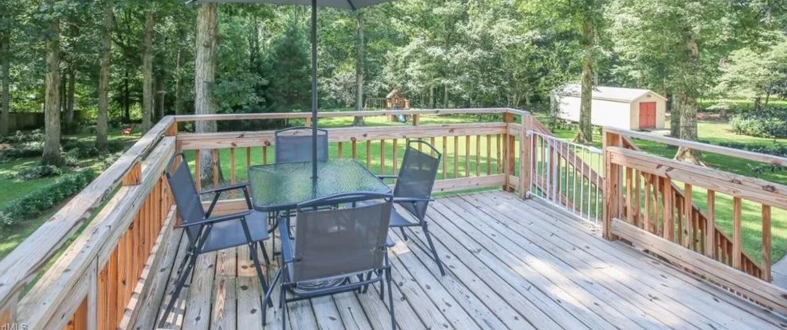 Backyard wood deck with patio seating overlooking the trees