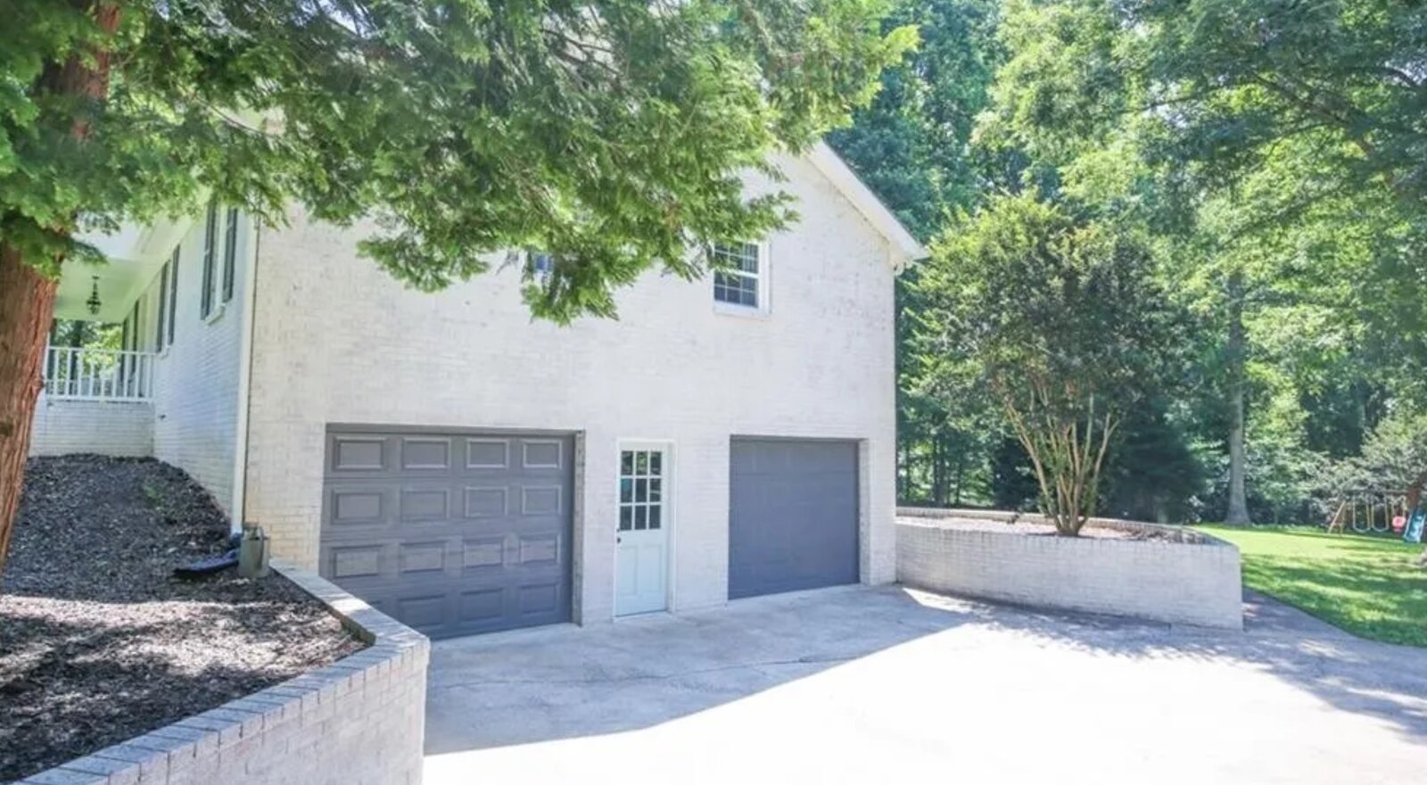 Painted brick ranch exterior with new gray garage doors and stamped driveway