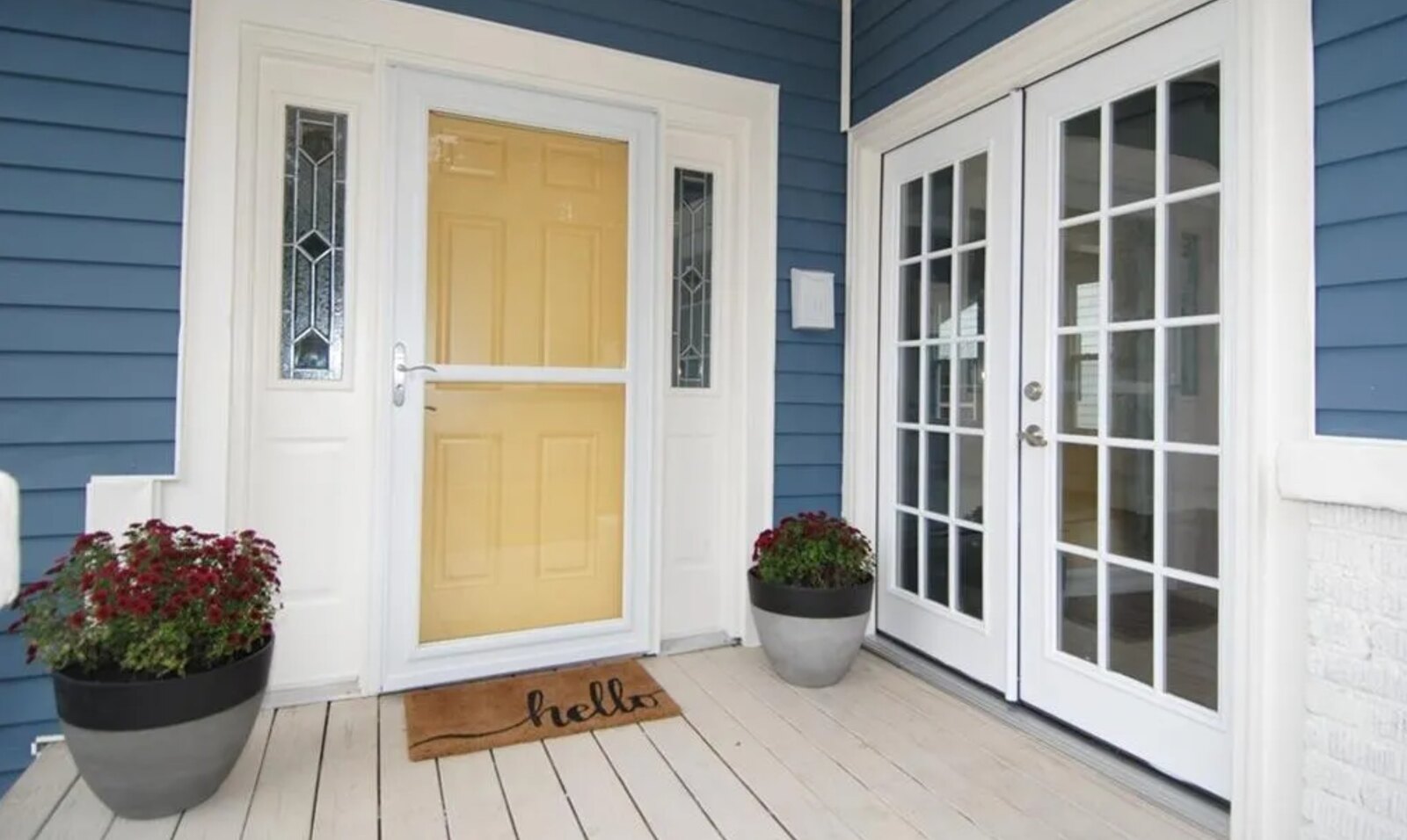 Charming blue siding porch with yellow front door and french doors