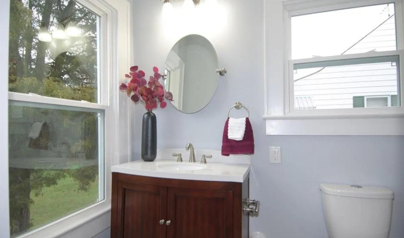 Renovated bathroom with wood vanity, round mirror and bright window