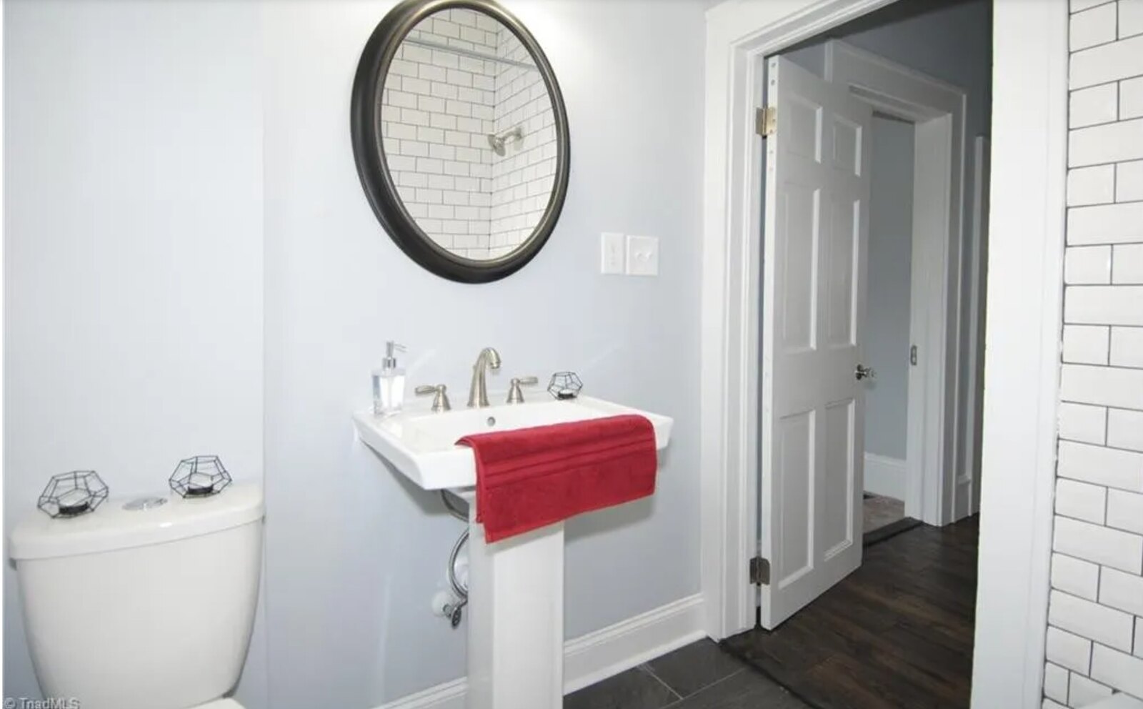 Half bath with pedestal sink, round bronze mirror and subway tile shower
