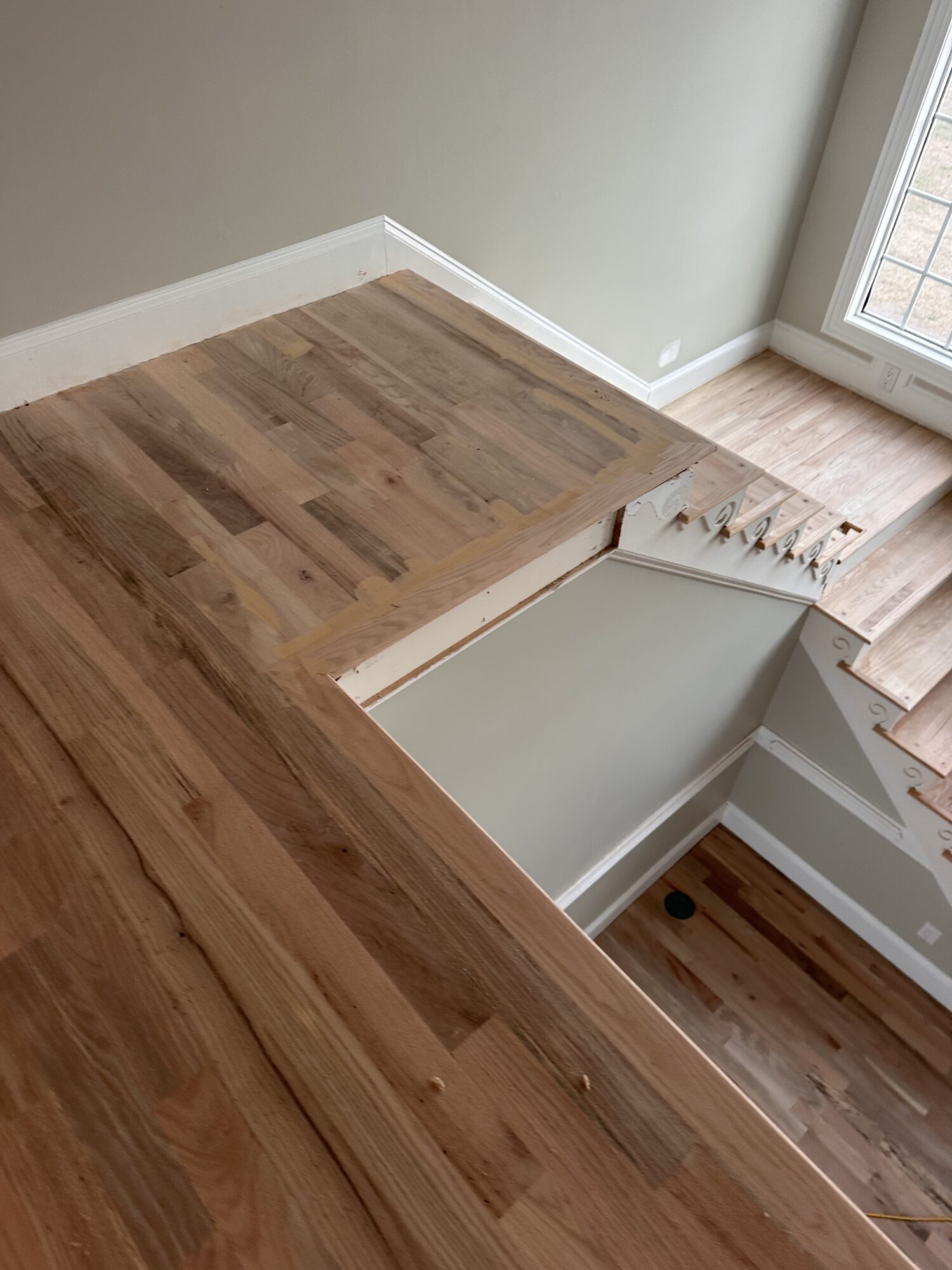 Before: hardwood flooring being sanded near staircase landing