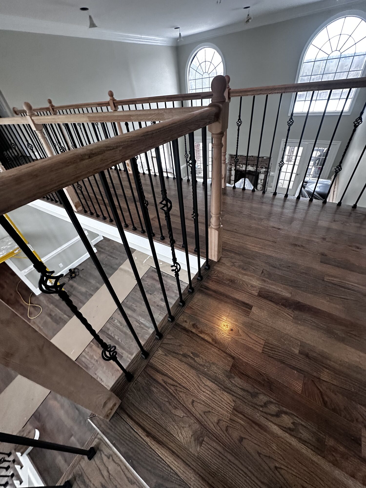 Before: raw hardwood installed on upper landing, looking down at staircase