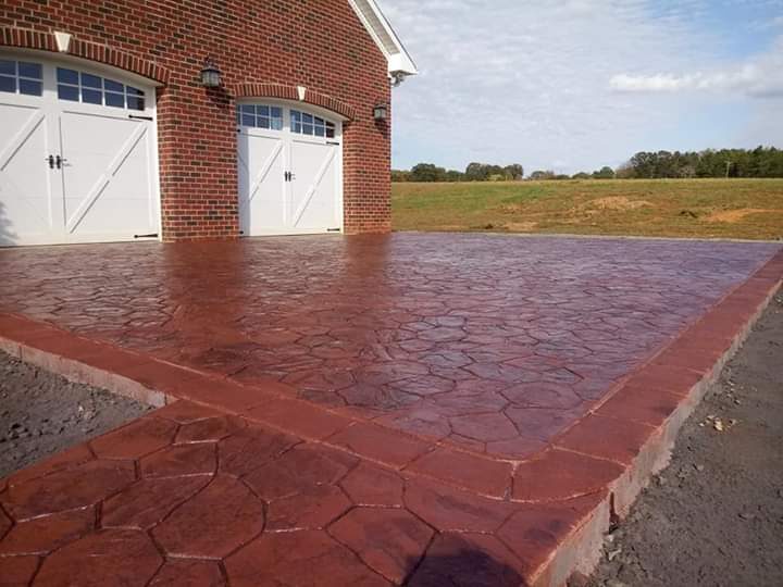 Finished: red-stained stamped concrete driveway at brick home with carriage-style garage doors